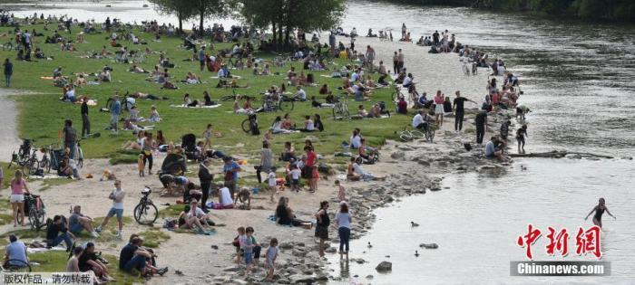 资料图：图为德国慕尼黑的伊萨尔河附近，人们在河边享受暖春天气。
