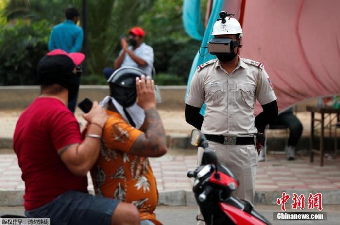 当地时间5月11日，印度新德里街头，为防止新冠肺炎疫情的扩散，警察带着一款特制头盔上岗，头盔顶端设有监控器，面部用除佩戴口罩外，还有一款链接手机的智能眼罩，只需看一眼就知道行人体温是否正常。