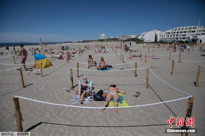 当地时间5月24日，在法国南部的拉格兰德莫特，在海滩上晒日光浴的人们躺在一个标志明显的区域内，以执行社交隔离措施。