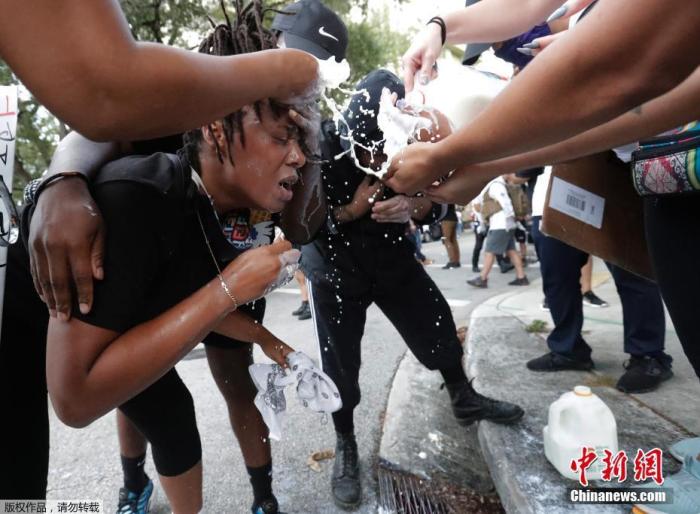 当地时间5月30日，美国迈阿密的示威活动中，人们帮助一名受催泪瓦斯影响的抗议者用牛奶洗眼睛。