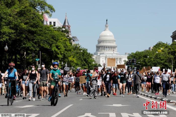 资料图：当地时间5月30日，美国华盛顿，抗议者高举标语从国会山朝白宫进发。