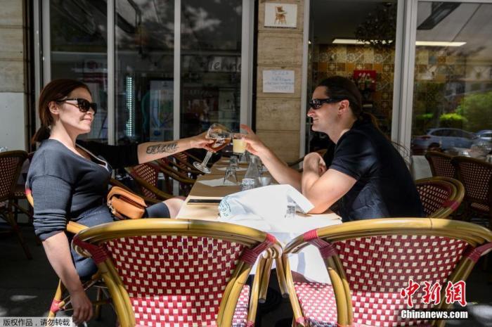 6月2日起，法国首都巴黎的咖啡馆、酒吧、餐馆重新开张，但只允许开放露天座。图为当地时间6月1日，两人在巴黎咖啡餐厅的露台上聚会。