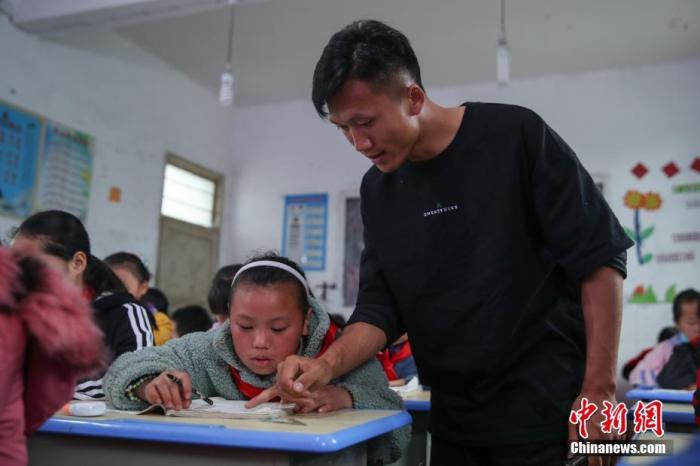 资料图：6月4日，贵州“90后”乡村教师彭有兴在辅导一名学生做课堂练习。
中新社记者 瞿宏伦 摄