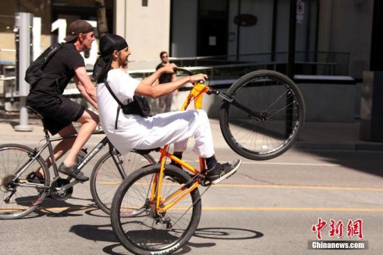 People play with their bicycles on a street in Toronto, Canada, June 6, 2020. (Photo/China News Service)