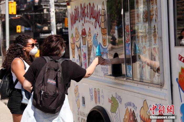 当地时间6月6日，顾客在加拿大多伦多街头的一辆雪糕车前购买冰激凌。随着经济逐步重启，多伦多市政府在这个周末到来之前宣布允许街头食品摊贩、快餐车和雪糕车恢复营业。 <a target='_blank' href='http://www.chinanews.com/'>中新社</a>记者 余瑞冬 摄