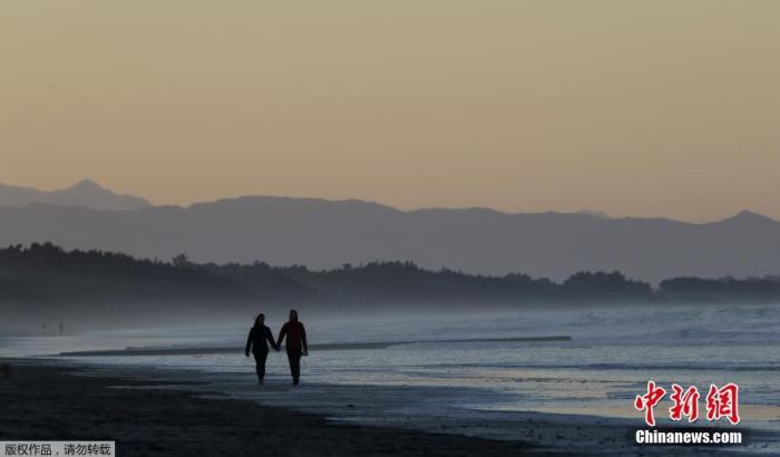 资料图：新西兰民众在海滩散步。