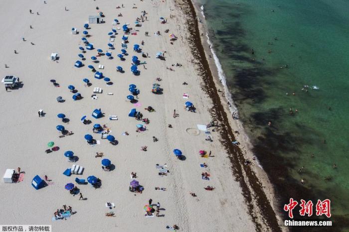 当地时间6月10日，佛罗里达州迈阿密海滩关闭近三个月后首次开放，工作人员在场提醒游客保持社交距离的前提下享受阳光沙滩。