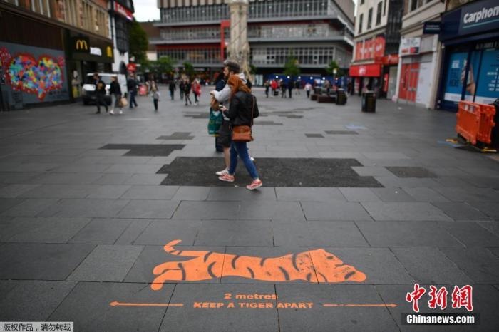 当地时间6月29日，英国莱斯特市中心的地面上印有提醒人们保持社交距离的标语。