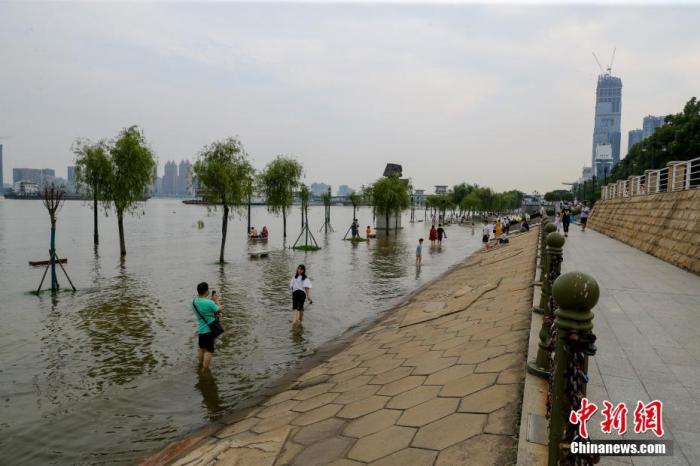 7月1日，武汉汉口江滩，部分市民、游客在汉口江滩一级亲水平台观水、嬉戏。连日来，受降雨和上游来水影响，长江武汉关水位持续上涨达到设防水位。中新社记者 张畅 摄