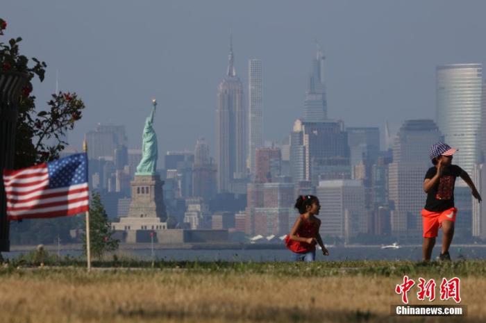 资料图：当地时间7月4日，两名孩童在纽约曼哈顿对岸的海滨草坪上奔跑。
中新社记者 廖攀 摄