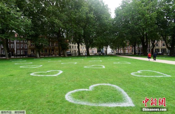当地时间2020年7月8日，英国布里斯托尔，艺术家在皇后广场的草地上画出心形图案，敦促人们保持社交距离。