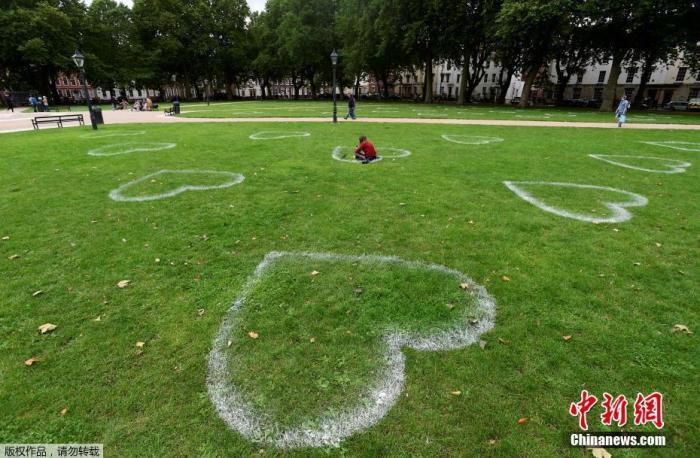当地时间7月8日，英国布里斯托尔，艺术家在皇后广场的草地上画出心形图案，敦促人们保持社交距离。