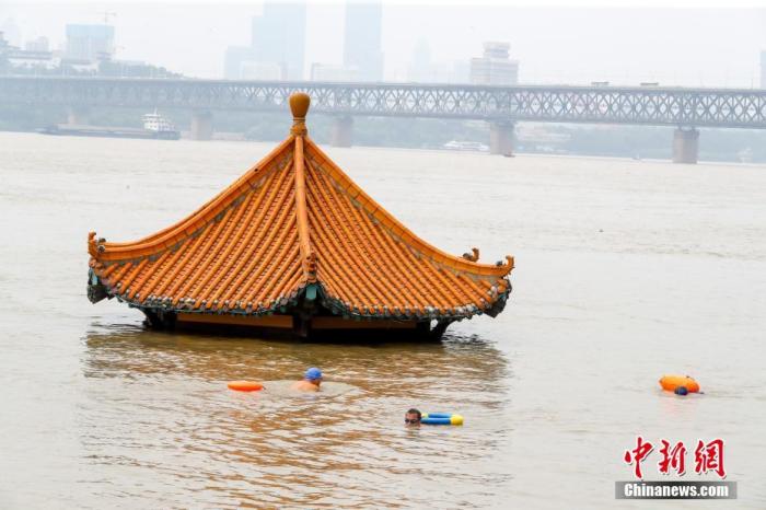7月10日，湖北武汉，市民游泳经过被洪水淹没的黄花叽亲水平台。受近期强降雨影响，长江中下游干流及两湖出口控制站水位持续上涨，超出警戒水位。
中新社记者 张畅 摄