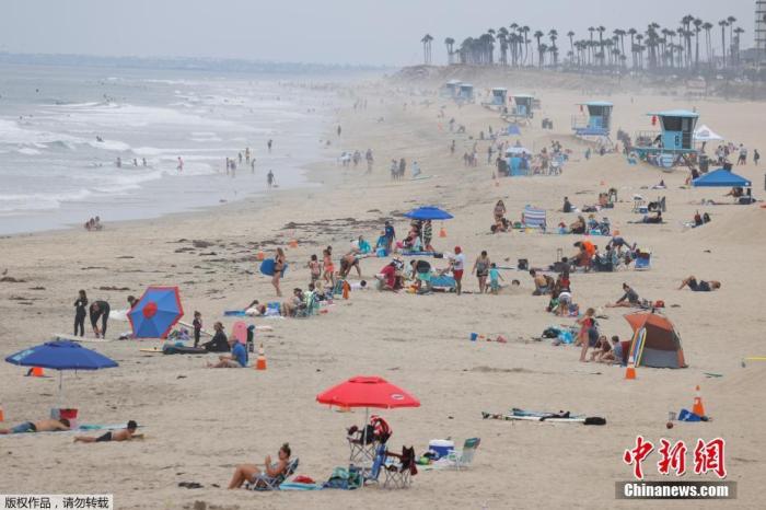 资料图：7月，美国加州亨廷顿海滩上的度假人群。