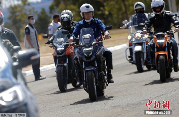 资料图：当地时间2020年7月25日，巴西巴西利亚，巴西总统博索纳罗宣布新冠肺炎检测结果为阴性后，骑摩托车出行。