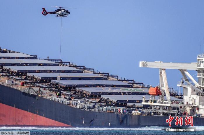 一架直升机在日本货船上方飞行，抽油作业仍在继续。