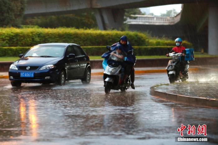 资料图：市民在雨中骑行。
中新社记者 富田 摄