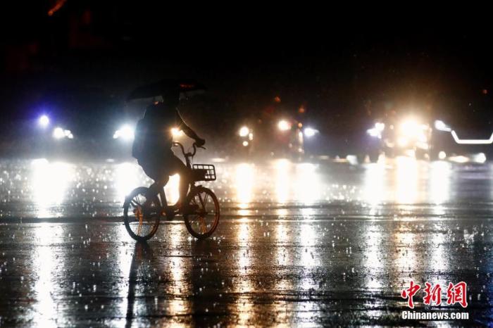 资料图：市民冒雨出行。中新社记者 盛佳鹏 摄
