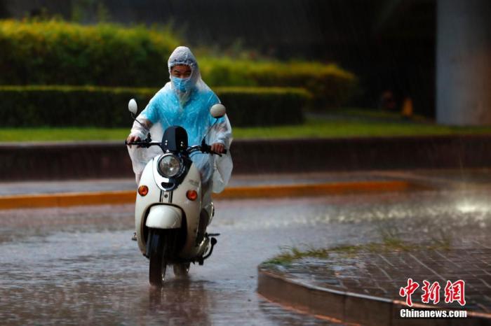 资料图：市民在雨中骑行。
中新社记者 富田 摄