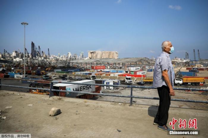 图为8月12日在黎巴嫩贝鲁特，一个戴着口罩的男子正在注视着大爆炸中被破坏的港口。