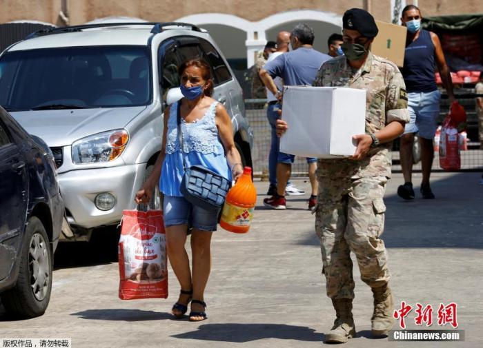 图为8月12日，黎巴嫩贝鲁特港口地区发生大爆炸后，一名妇女从军队领取分发的援助物资。
