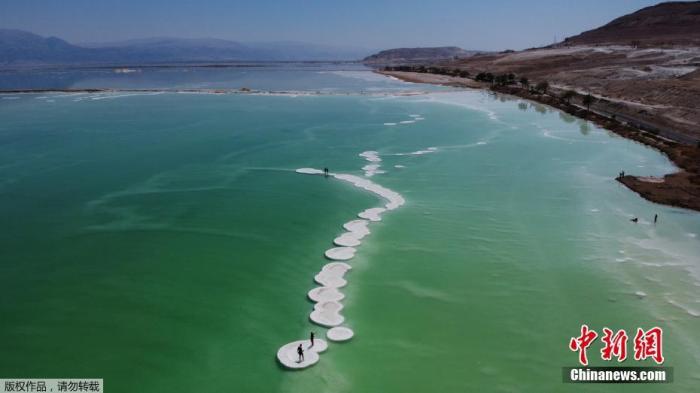 8月25日，以色列Ein Bokeq附近，海滩游客站在死海盐层上。
