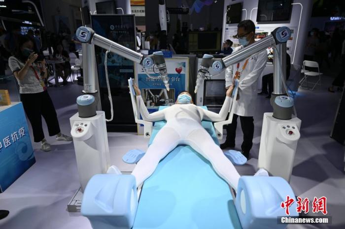 资料图：9月5日，2020年服贸会展区，工作人员在中医智能经络导引台演示机器人帮助“患者”按摩经络。 中新社记者 张兴龙 摄