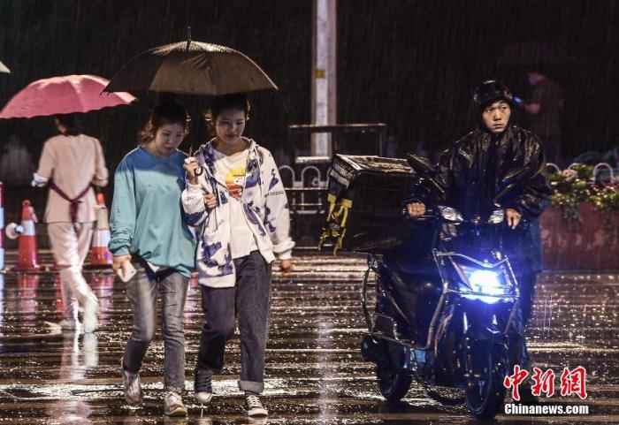 资料图：市民在雨中出行。图片来源：视觉中国
