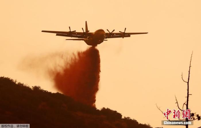 当地时间9月17日，美国加利福尼亚州杜松山附近，一架运输机投放阻燃剂以限制“山猫”野火蔓延。