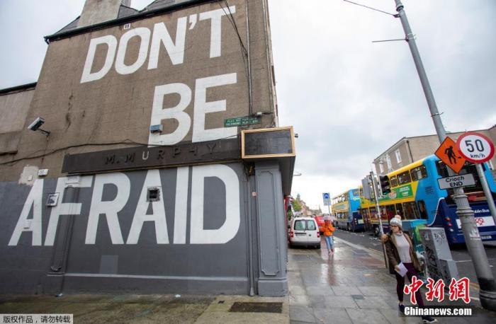资料图：爱尔兰都柏林街头，行人走过写有“不要害怕”的标语。