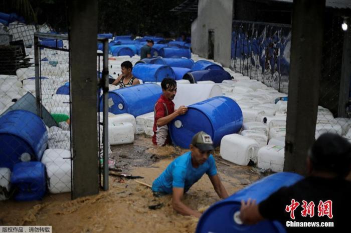 当地时间11月4日，洪都拉斯持续遭遇飓风“埃塔”，给当地带来暴雨。人们在收集被洪水冲走的塑料桶。