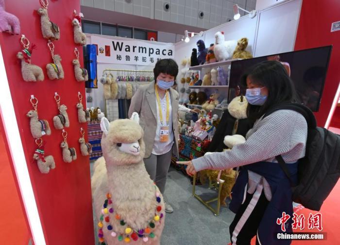 一名参会者走进参展商马玉霞（左）的展台，咨询秘鲁羊驼毛产品。中新社记者 侯宇 摄