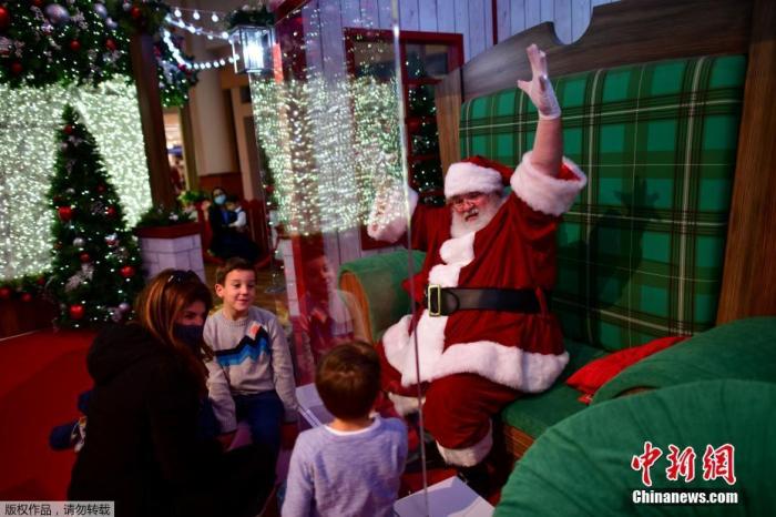 当地时间11月14日，美国宾州一家购物中心内，圣诞老人的面前竖起了一块树脂玻璃，小朋友隔着玻璃与圣诞老人互动合影。