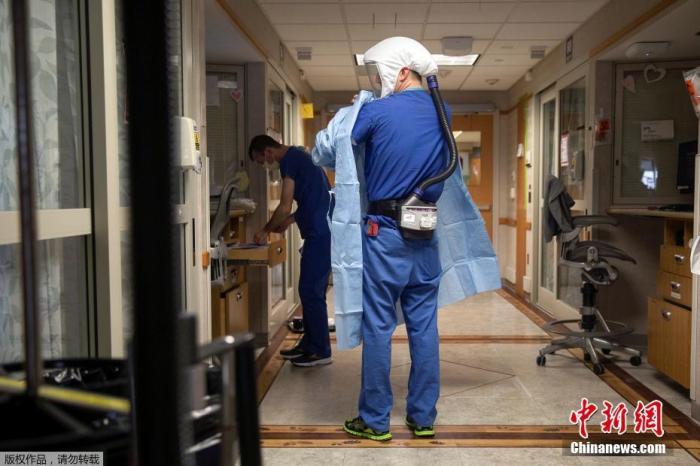 当地时间11月18日，美国威斯康辛州麦迪逊华盛顿大学卫生大学医院，医护人员在进入新冠肺炎患者病房前，佩戴电动空气净化呼吸器。