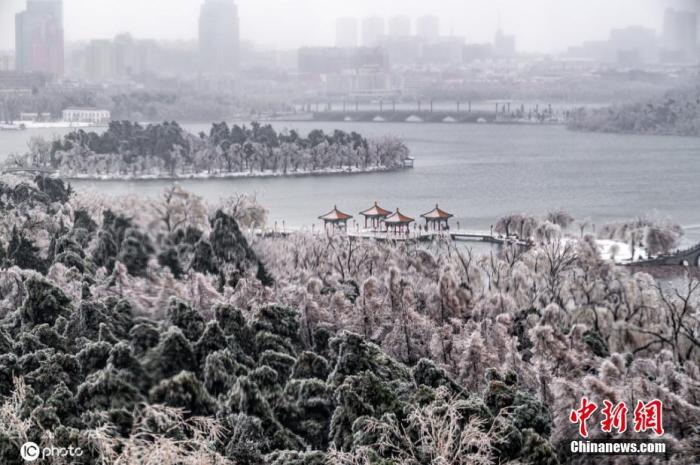 11月19日，吉林省长春市，遭遇雨雪降温极端天气。雪后的大街小巷，各种建筑物和植被上满满的都是薄冰，形成晶莹剔透的冰挂，美丽如画，市民纷纷出门赏雪景。图片来源：ICphoto