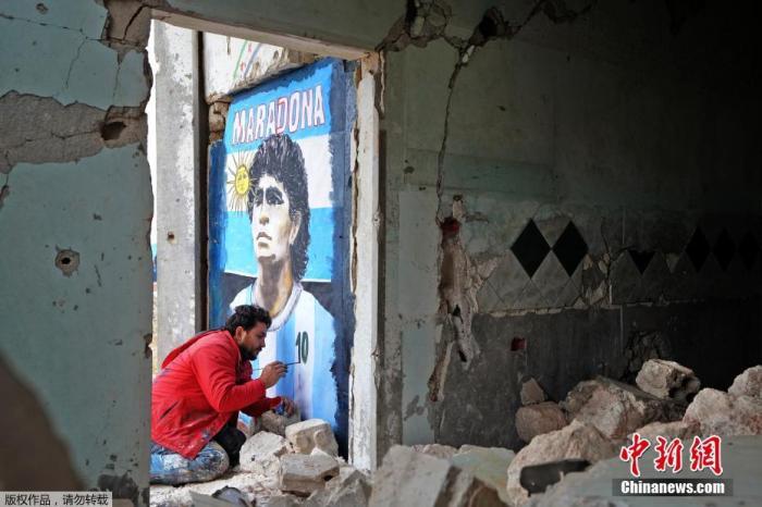 11月26日，叙利亚西北部伊德利卜省宾尼什镇的废墟上，叙利亚画家阿齐兹·阿斯玛(Aziz Asmar)正在为逝世的“球王”马拉多纳画像。
