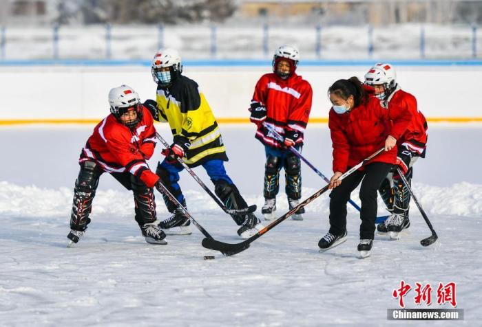 12月11日，在新疆阿勒泰地區富蘊縣體育館室外冰場，教練周曉鳳(前右)帶領青少年冰球隊的隊員訓練。據介紹，該青少年冰球隊成立于2014年，目前有50余名中小學生隊員。近年來，該縣在中小學中推廣雪地足球、滑冰、滑雪、冰球等冰雪運動，引領學生參與冰雪活動，培養冰雪運動興趣，提高冰雪運動技能。
中新社記者 劉新 攝