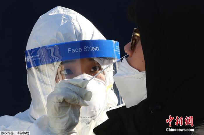 当地时间12月14日，韩国首尔，医务人员正对一名市民进行新冠病毒检测。