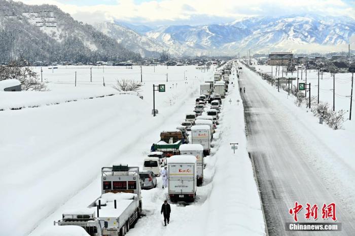 当地时间2020年12月18日，日本新潟市南鱼沼市遭遇暴雪，大量车辆被堵在路上，扫雪工作已同步展开。 图片来源：视觉中国