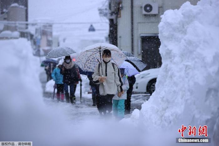 资料图：日本新潟县的学生在雪天行走。