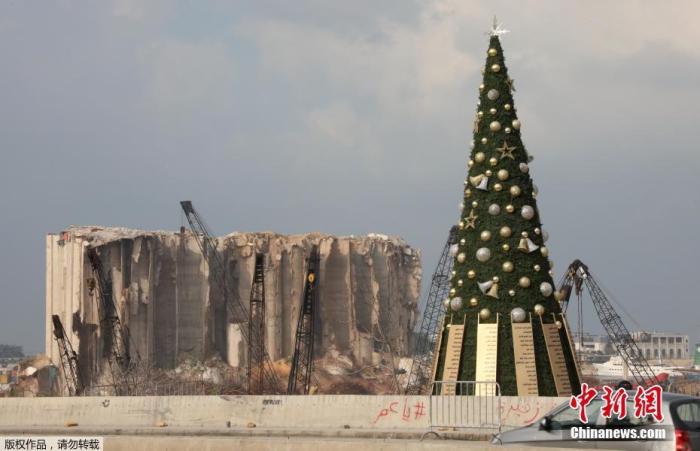 当地时间2020年12月22日，黎巴嫩首都贝鲁特，一颗巨大的圣诞树立于曾在贝鲁特港口大爆炸中受损的粮仓附近。圣诞树上除了常规的装饰品之外，挂上了在爆炸中逝者的名字。