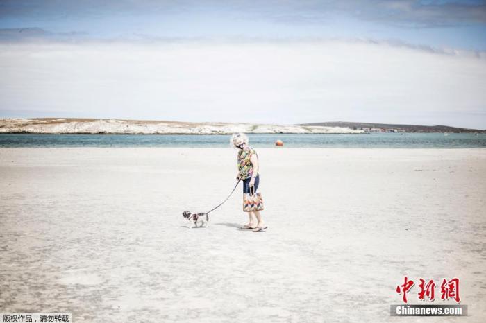 资料图：2020年12月29日，南非兰格班，一名老妇人在空旷海滩短暂地遛狗。