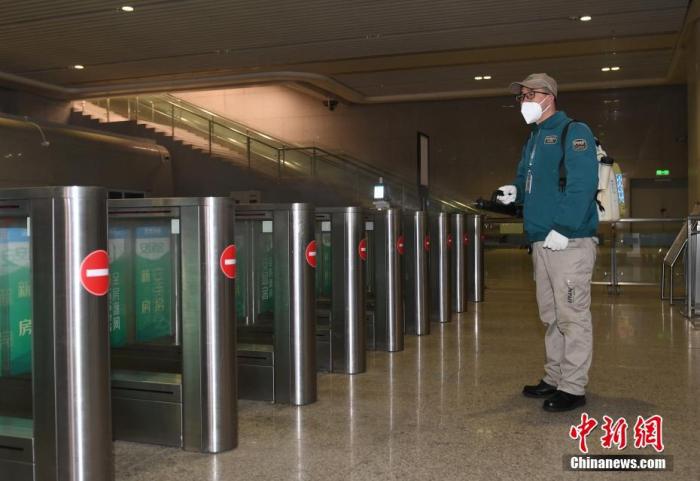1月11日，浙江杭州，一名工作人员在杭州东站出站口对闸机进行消毒。中新社记者 王刚 摄
