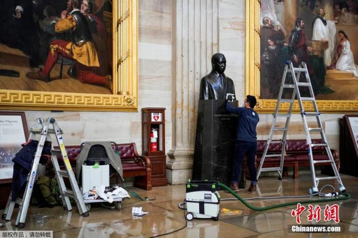 图为当地时间1月12日，美国华盛顿，建筑师在国会大厦圆形大厅清理小马丁·路德·金半身像上的灰尘。