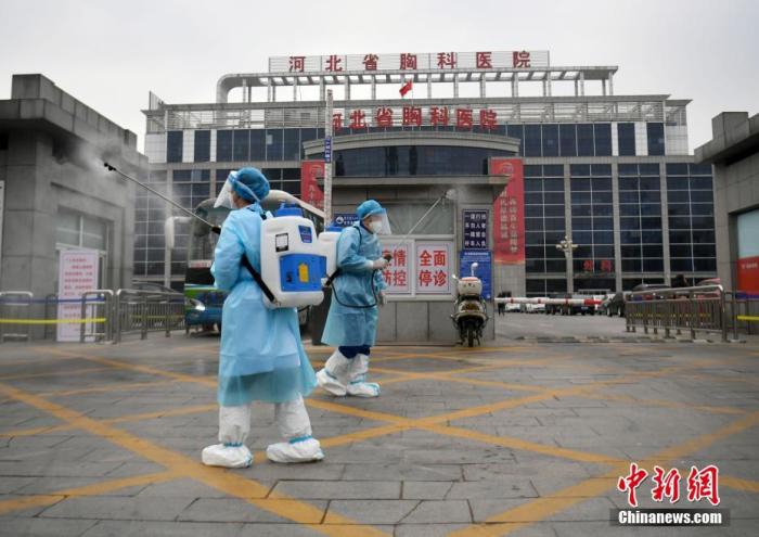 1月19日，河北石家庄，河北省胸科医院的工作人员在医院大门口消毒。
中新社记者 翟羽佳 摄
