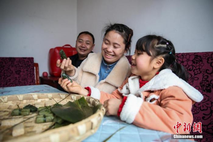 图为2月4日，贵州黔西化屋村村民赵玉学（左一）一家在制作黔西名小吃“黄粑”。
中新社记者 瞿宏伦 摄