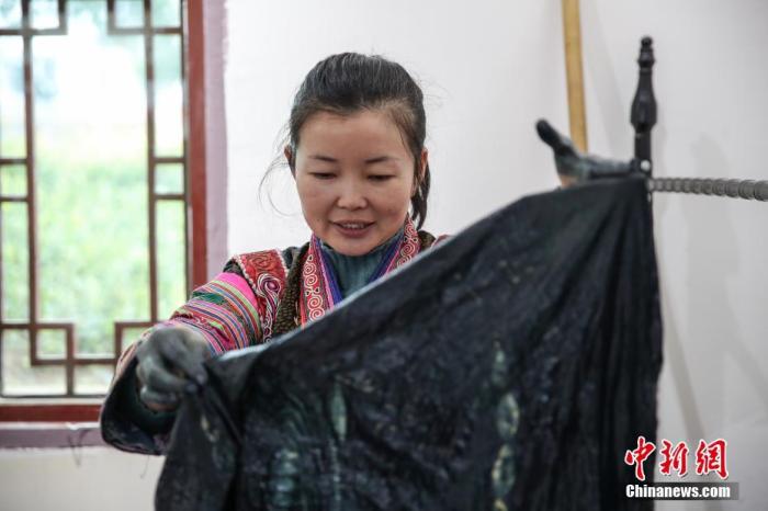 图为2月4日，贵州黔西化屋村扶贫车间擅长蜡染工艺的彭艺在染制产品。
中新社记者 瞿宏伦 摄