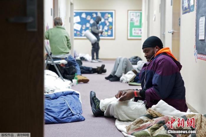 当地时间2月18日，美国得克萨斯州普莱诺因冬季天气导致停电后，人们在避难所里休息。图为一名避难者准备吃饭。
