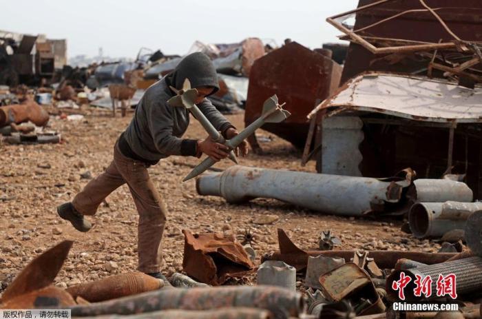 当地时间3月10日，叙利亚伊德利卜省西北部马雷特米斯林镇郊区的一个金属废料场上，人们正在整理堆放的废料。据悉，一个叙利亚家庭4年前从哈马北部农村的Latamneh村搬迁到这里后，通过收集和出售包括未爆弹药壳和废弹药壳在内的金属废料获得收入。图为一个男孩在整理废料。