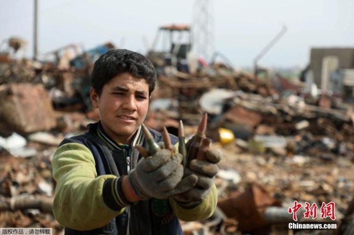 资料图：叙利亚伊德利卜省西北部一处金属废料场上，一名叙利亚男孩展示子弹弹壳。